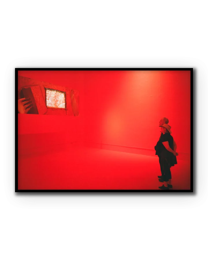 Fotografía artística de dos visitantes observando una instalación roja en un museo contemporáneo